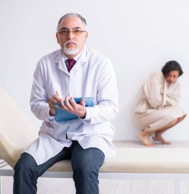 Genç hastayı muayene eden yaşlı erkek psikiyatrist.