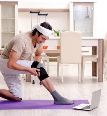 Evde egzersiz yapan yaralı genç adam.