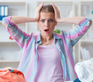 Evdeki kıyafetleri ütüleyen üzgün kadın.