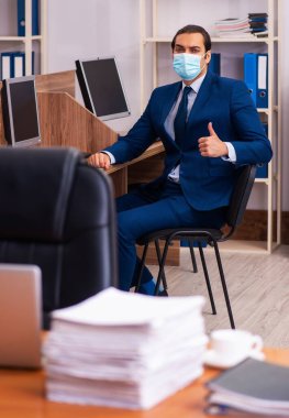 Ofiste maske takan genç bir çalışan.