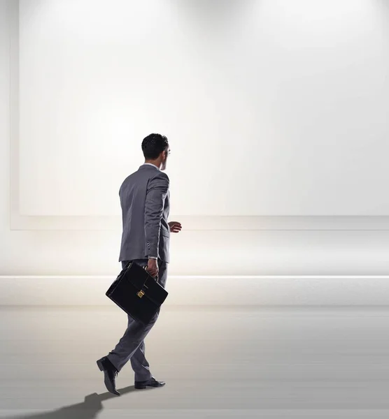 stock image The businesswoman walking towards the wall lit with spotlights