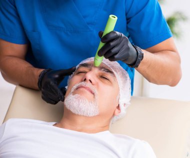 Yaşlı adam estetik ameliyat için doktoru ziyaret ediyor.