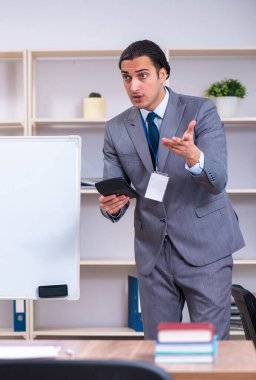 Beyaz tahtanın önünde duran genç iş adamı.