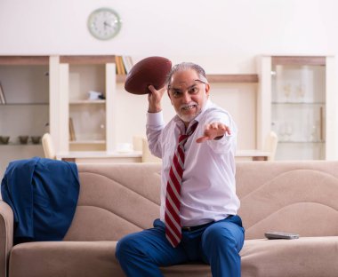 Üst düzey erkek patron evde rugby topu atıyor.