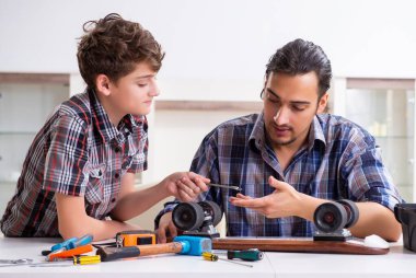 Genç baba oğluyla birlikte kaykay tamir ediyor.