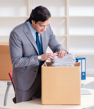 The young man employee with boxes in the office