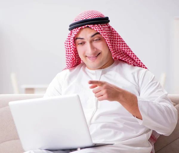 那个拿着笔记本电脑在沙发上工作的年轻的阿拉伯商人 — 图库照片