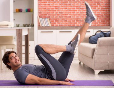 Genç yakışıklı adam evde spor egzersizleri yapıyor.