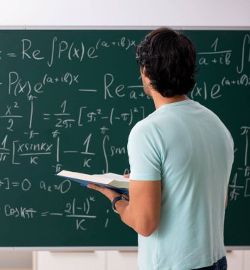 Tahtanın önündeki genç erkek matematikçi.