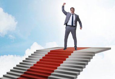 Genç işadamı merdivenleri tırmanıyor ve gökyüzüne kırmızı halı seriliyor.