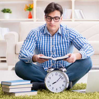 Genç yakışıklı adam evde yerde oturuyor.