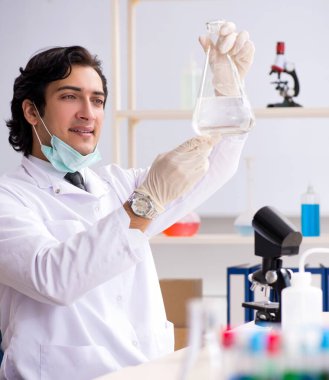 Laboratuvarda çalışan genç yakışıklı kimyager.