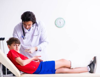 Bacağı yaralı çocuk genç doktor travmatoloğu ziyaret ediyor.