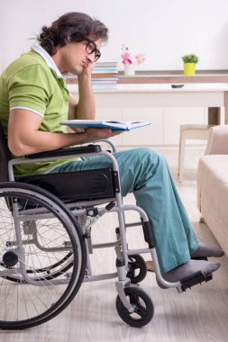 Evdeki tekerlekli sandalyedeki genç erkek öğrenci.