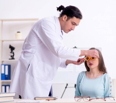 Erkek doktor göz doktorunu ziyaret eden genç kadın.