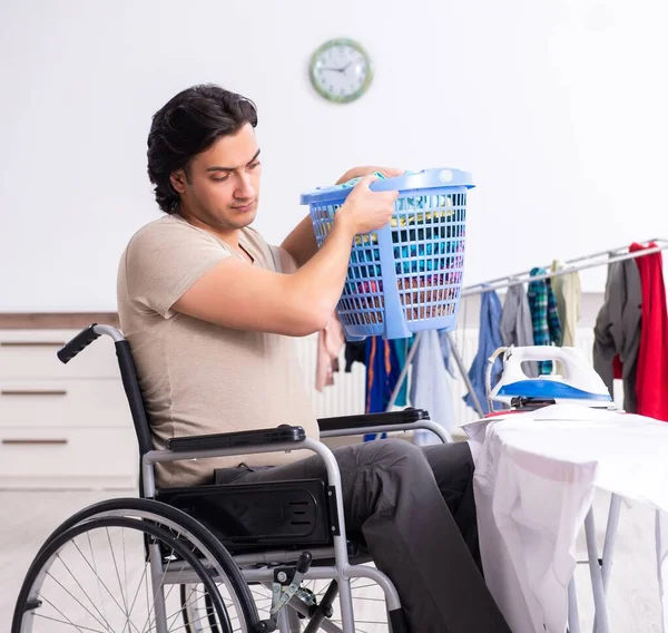 stock image The young man in wheel-chair doing ironing at home