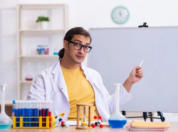 Young chemist teacher in front of white board