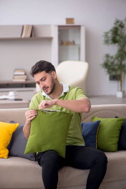 Evde bir sürü yastığı olan genç bir adam.