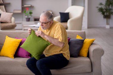 Evde bir sürü yastığı olan yaşlı bir adam.