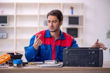 Atölyede bilgisayar tamir eden genç bir tamirci.