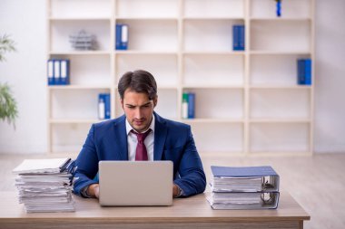 Genç işadamı ve işyerinde çok fazla iş var.