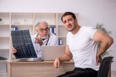 Genç hasta yaşlı erkek doktor radyolojisti ziyaret ediyor.