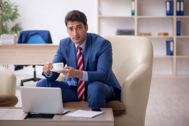 Genç işadamı işyerinde oturuyor.