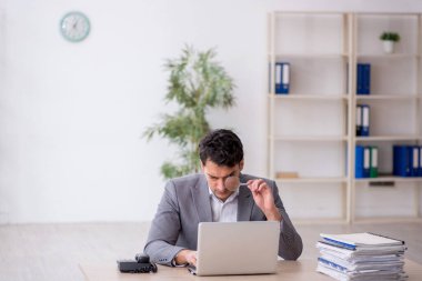Young employee and too much work at workplace