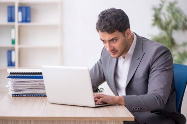 Young employee and too much work at workplace