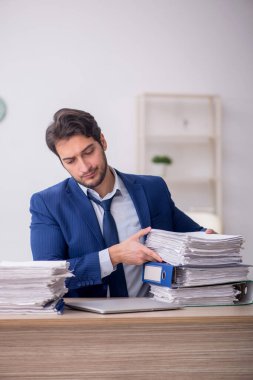 Young employee and too much work at workplace