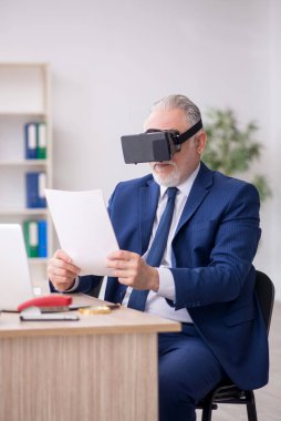 Old businessman employee wearing virtual glasses in the office