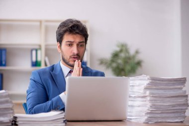 Young employee and too much work at workplace