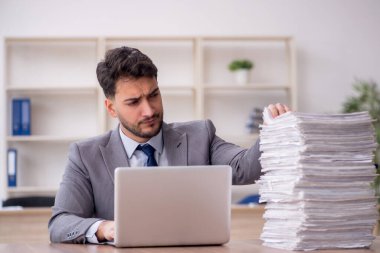 Young employee and too much work at workplace