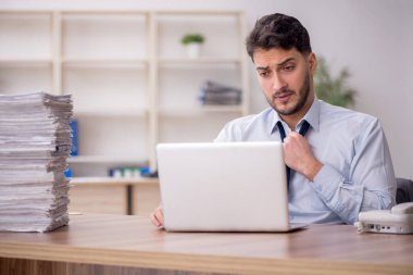Young employee and too much work at workplace