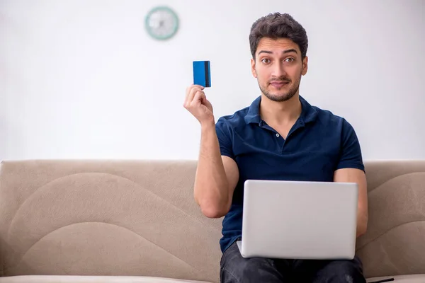 Young man holding credit card at home