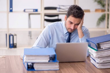 Young employee and too much work at workplace