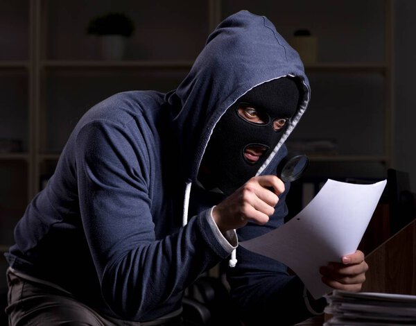 The male thief in balaclava in the office night time