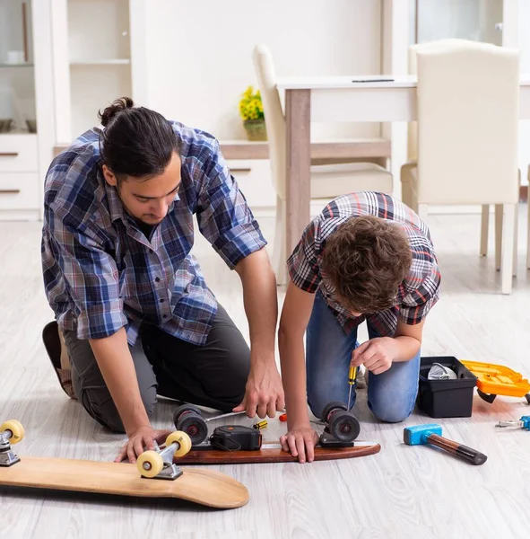 那位年轻的父亲和他的儿子在家里修理滑板 — 图库照片
