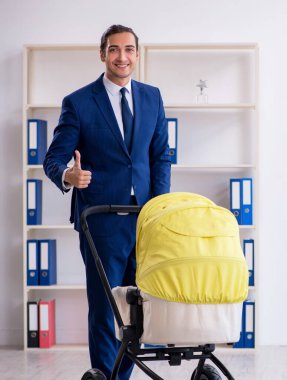 Ofiste yeni doğan bebeğe bakan genç baba.