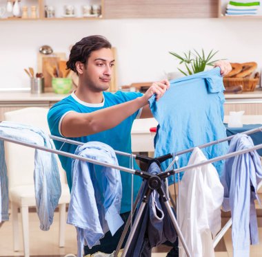 Genç adam evde ütü yapıyor.