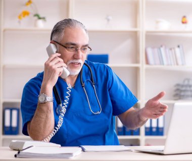 Klinikte çalışan beyaz sakallı yaşlı doktor.