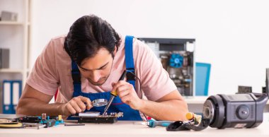 Genç erkek müteahhit bilgisayarı tamir ediyor.