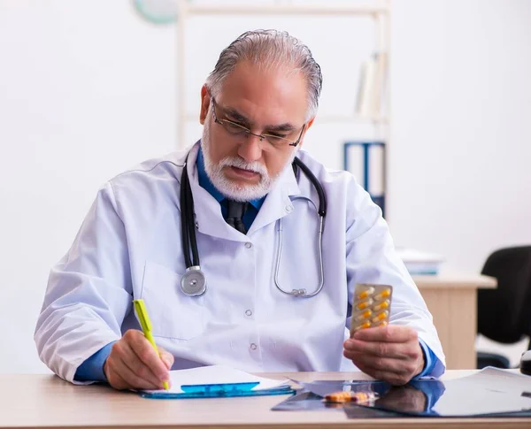 Senior male doctor writing prescription in the clinic
