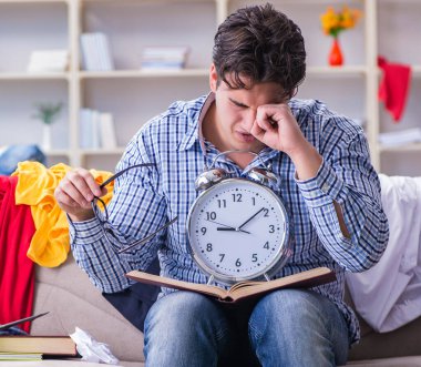 Dağınık odada çalışan genç adam.