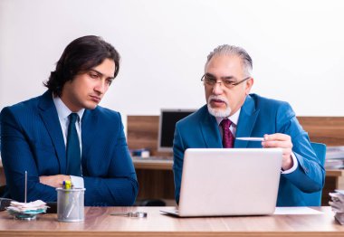 Genç ve yaşlı çalışanlar ofiste birlikte çalışıyorlar.