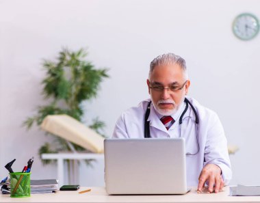 Klinikte çalışan yaşlı bir doktor.