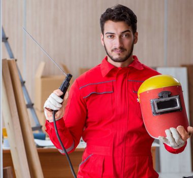 Kaynak tabancası elektrodu ve kaynak metali olan genç bir tamirci.