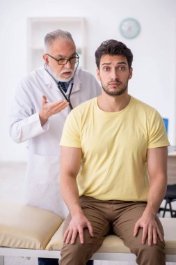Genç hasta yaşlı doktoru ziyaret ediyor.