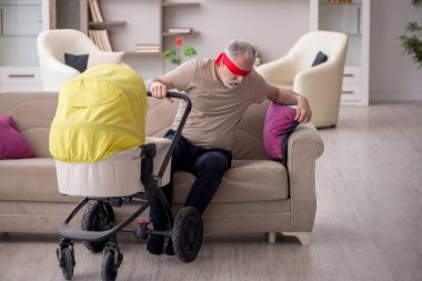 Evde yeni doğan bebeğe bakan yaşlı bir adam.