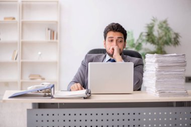Young employee and too much work at workplace